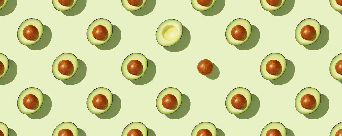 Banner. Avocado on green background pattern top view lay flat. Summer colour. Minimal concept