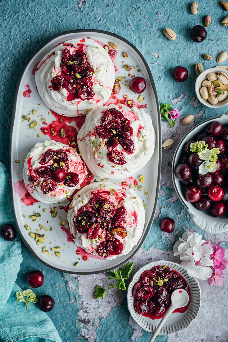 Meringues mit frischer Sahne und reifen Kirschen auf blauem Hintergrund