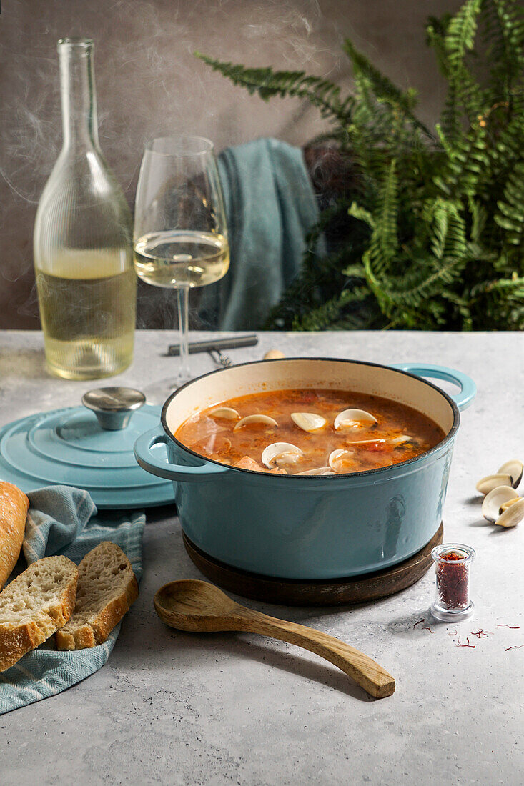 Französische heiße Suppe Bouillabaisse mit Venusmuscheln, Fischsuppe in gusseiserner Pfanne