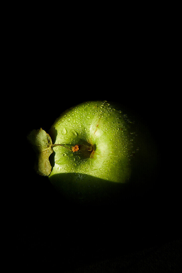 Green apple against a black background