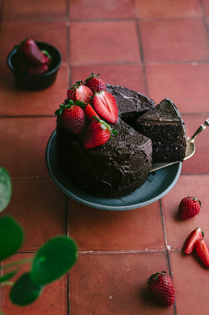 Schokoladenkuchen mit frischen Erdbeeren vor einem Terrakotta-Hintergrund