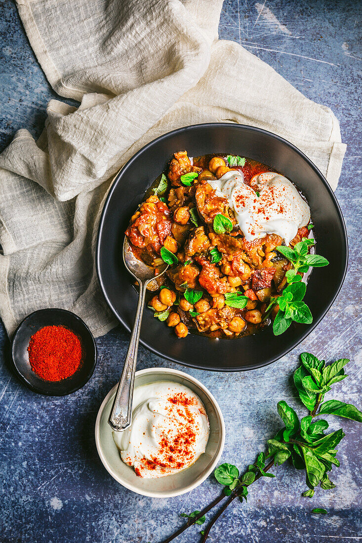 Braised aubergine and chickpea stew in a bowl garnished with yoghurt and mint
