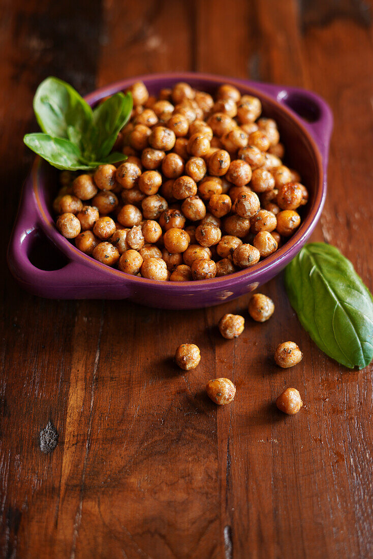Basil and paprika roasted chickpeas on wooden background.