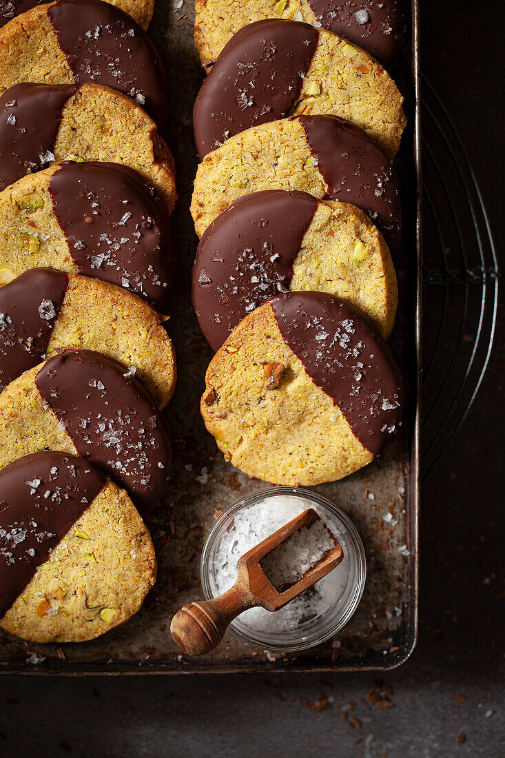 An old baking tray with pistachio biscuits dipped in chocolate and sprinkled with sea salt