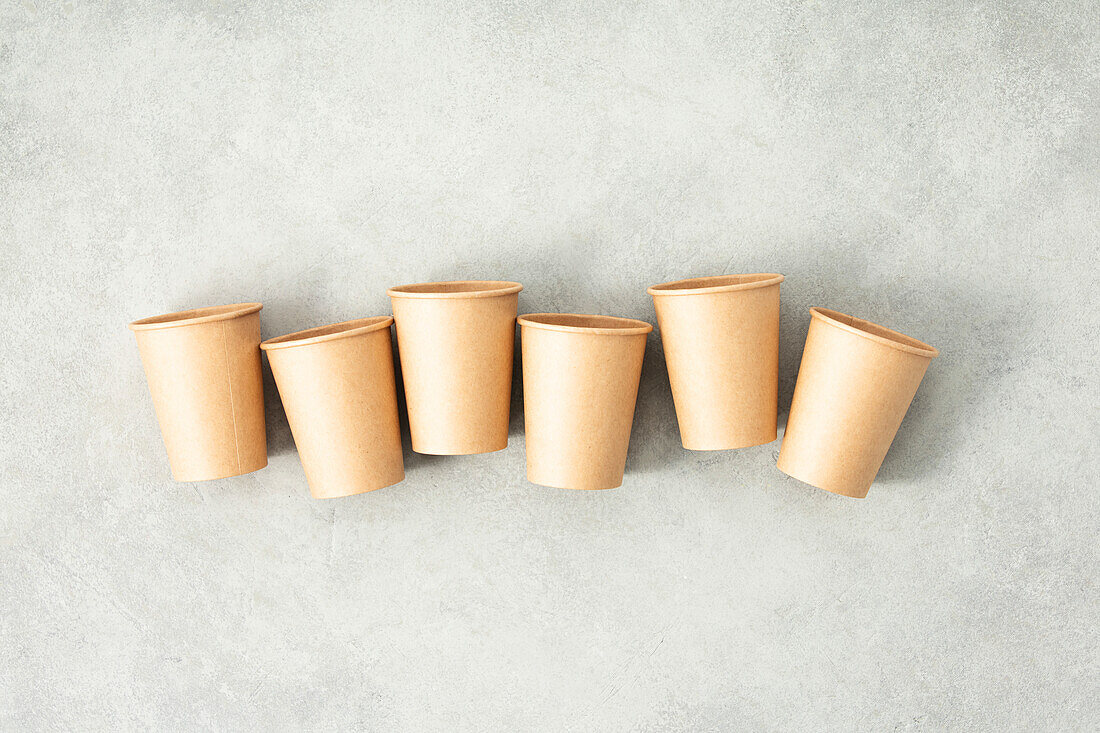 Flat lay composition with eco-friendly paper cups on grey stone background. Abfallfreies Verpackungskonzept