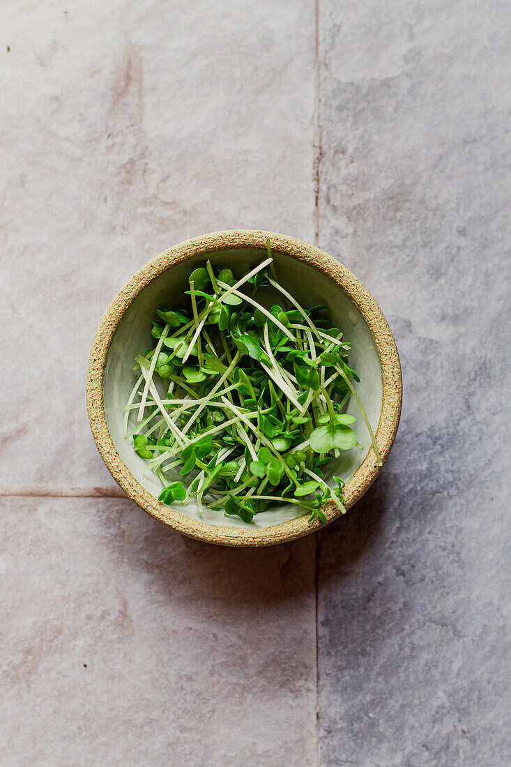 Flatlay of a small bowl of watercress on a tiled surface