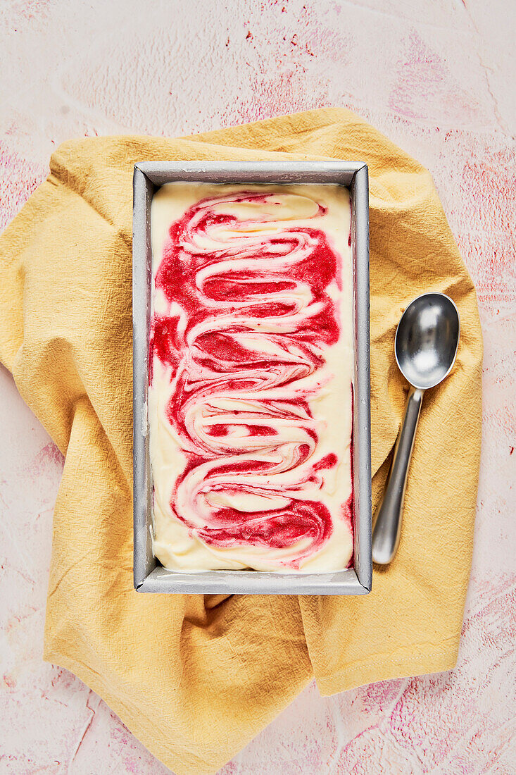 Raspberry Ripple Ice Cream Tub on a pink background with yellow napkin