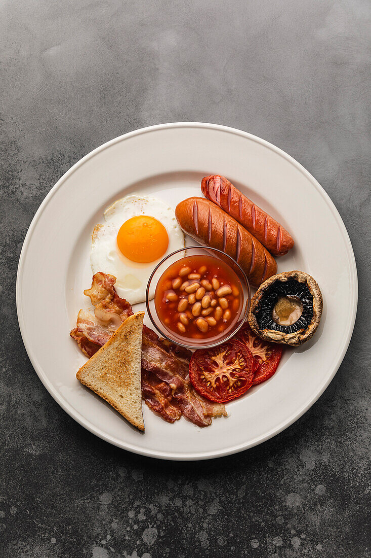 Komplettes englisches Frühstück mit Spiegeleiern, Würstchen, Speck, Bohnen und Toast