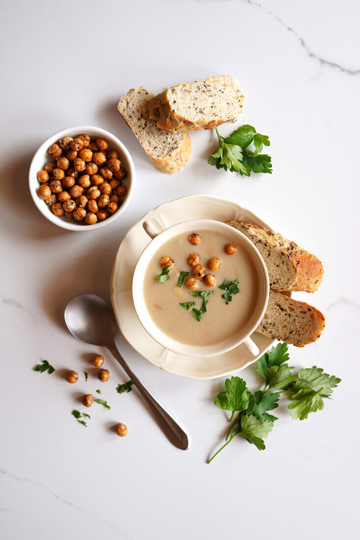 Vegane Blumenkohl-Kreuzkümmel-Limabohnen-Suppe auf weißer Marmorplatte. Einzelne Portion Flatlay