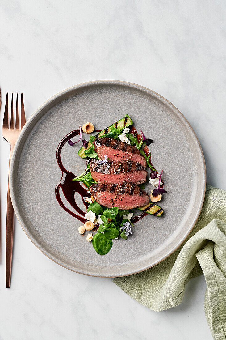 Ras el Hanout lamb fillet, balsamic glaze, Persian fetta, grilled courgette, rocket, watercress and roasted hazelnuts