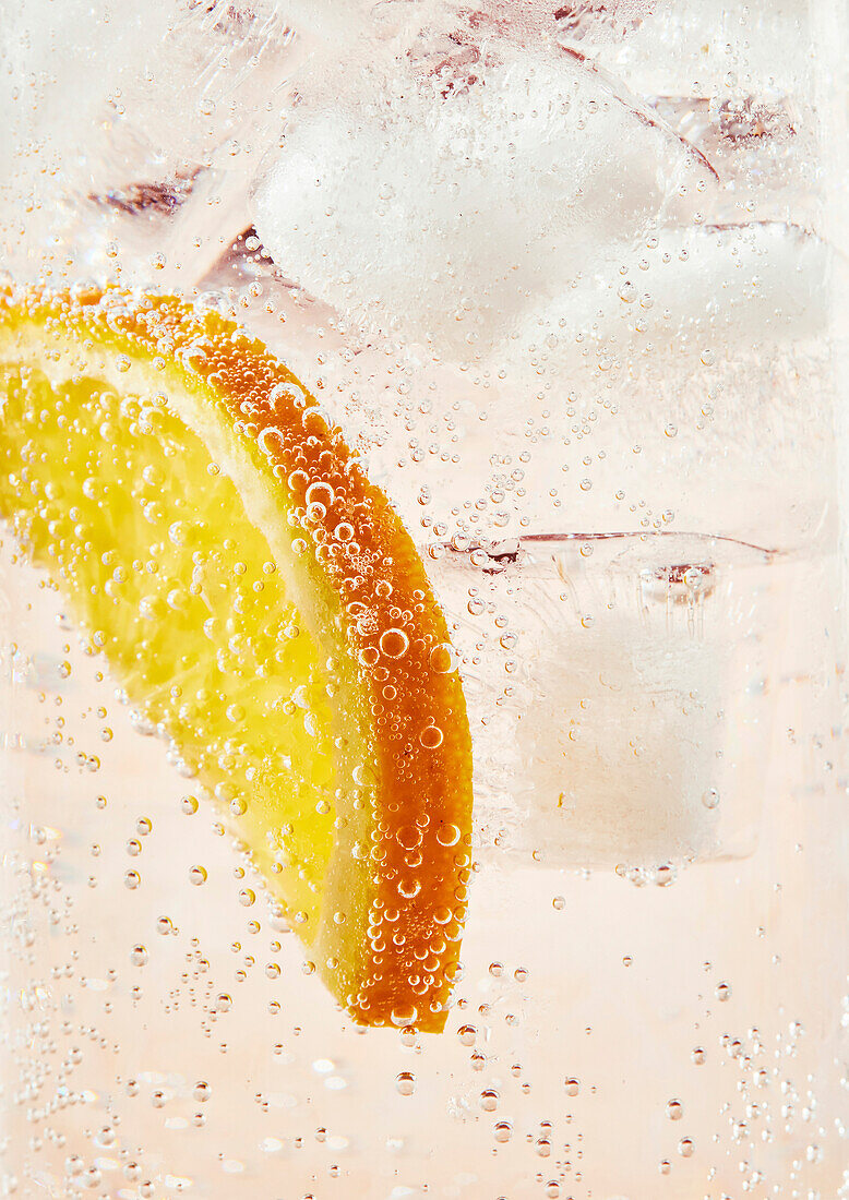 Lemonade in a glass with fizzy bubbles and a slice of orange