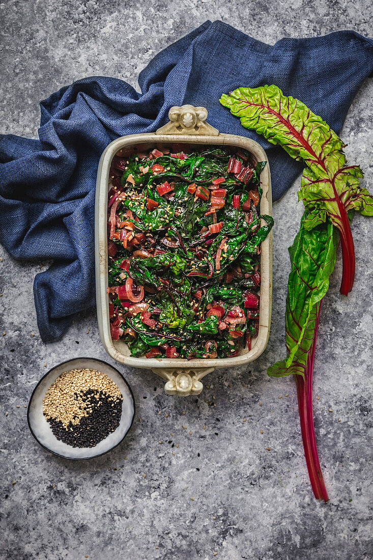 Steamed chard in antique bowl with napkin and fresh chard leaves