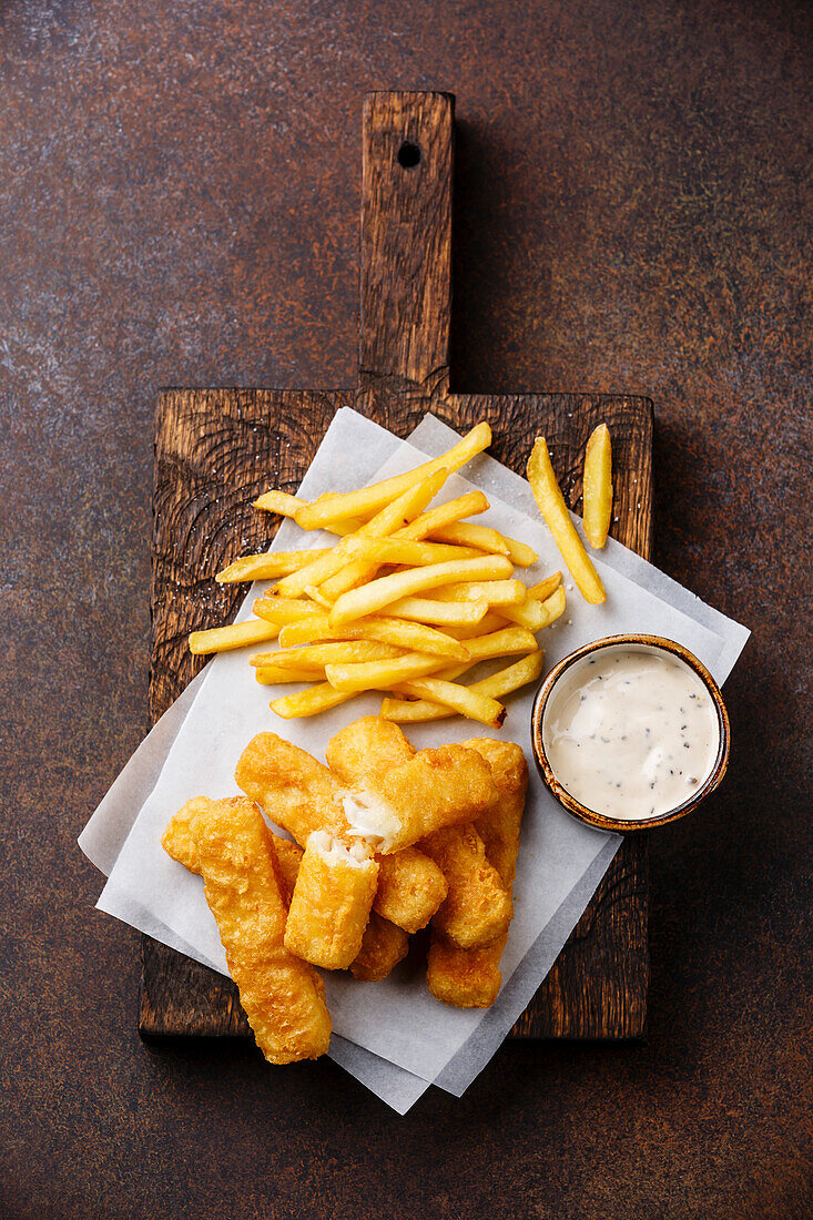 Fischstäbchen und Pommes frites britisches Fast Food mit Remoulade auf dunklem Hintergrund