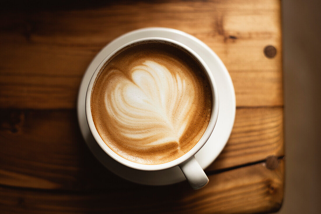 Coffee in a white cup on a wooden table, with spoon