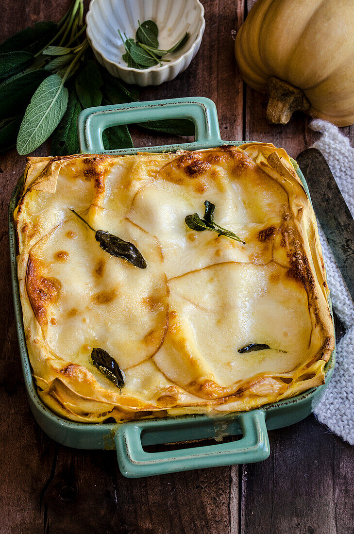 Pumpkin lasagne in a colourful cooking pan on a wooden table