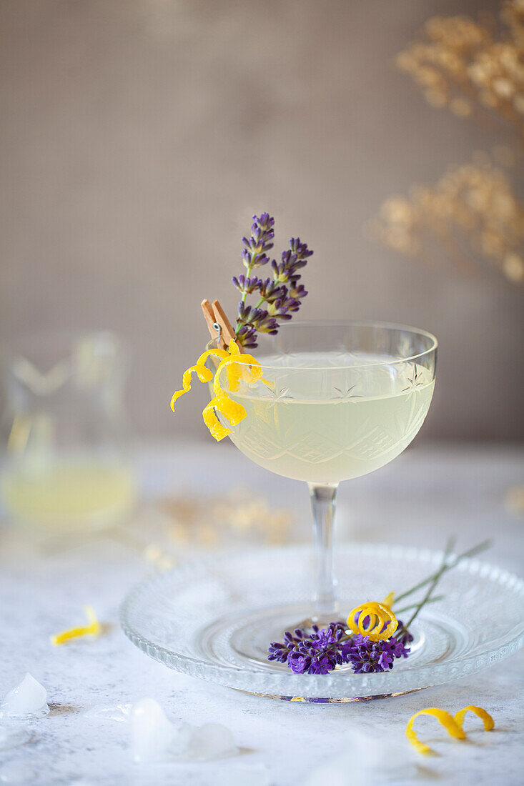 A vodka, lemon and lavender cocktail garnished with lemon zestand fresh lavender sprigs.