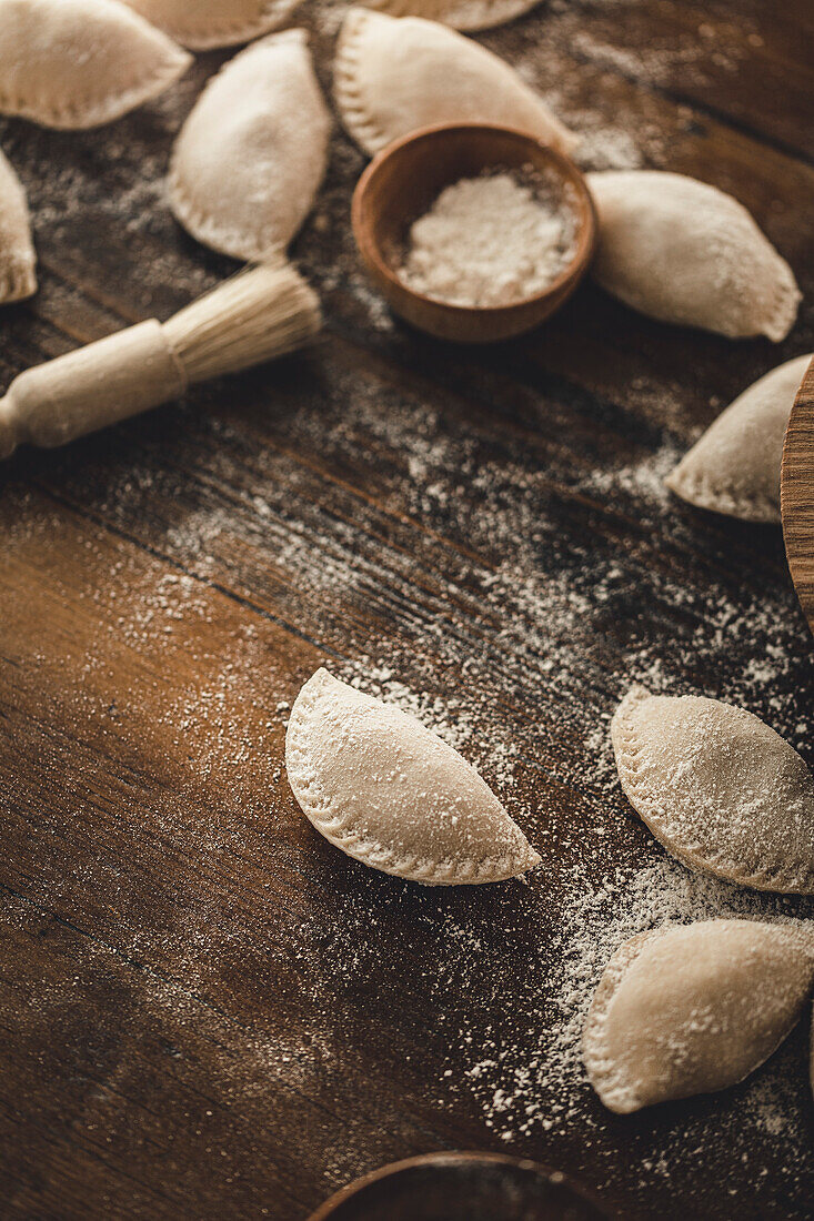 Piroggen in der Herstellung auf einem hölzernen Hintergrund