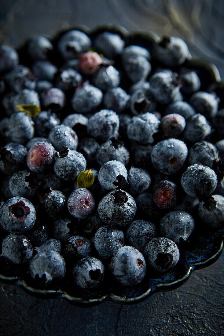 Blaubeeren mit Wassertröpfchen vor blauem Hintergrund