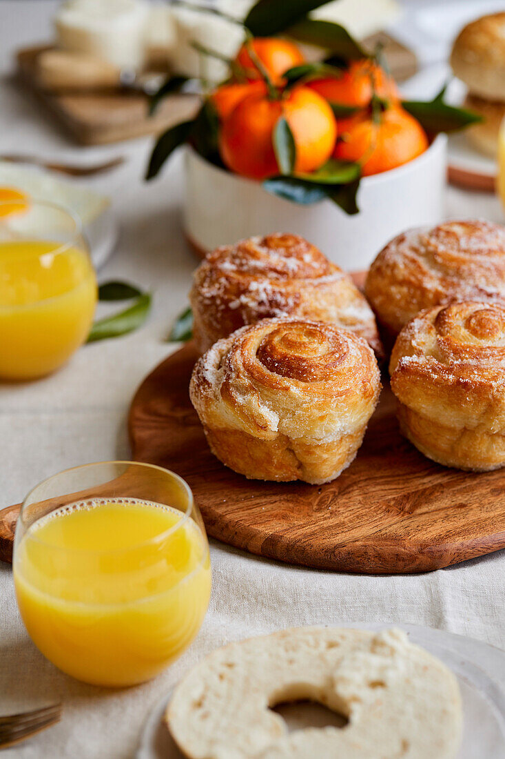 Frühstückstischlandschaft mit Gebäck, Orangensaft und Obst