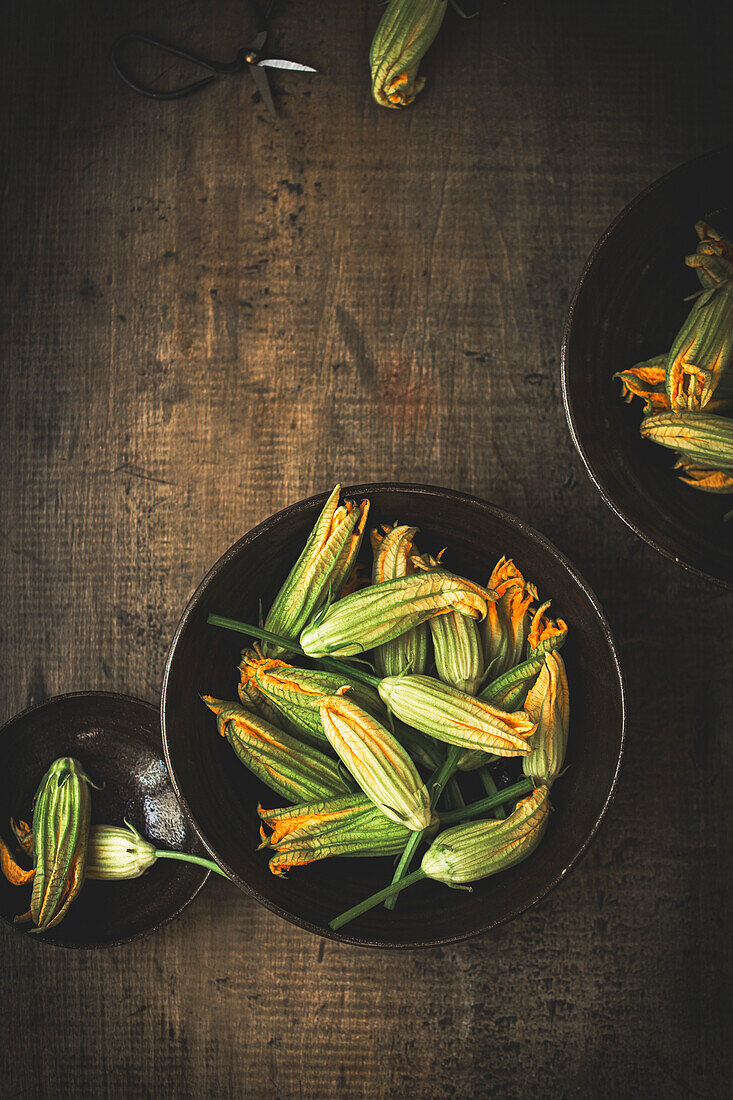 Zucchiniblüten vor einem rustikalen Holzhintergrund