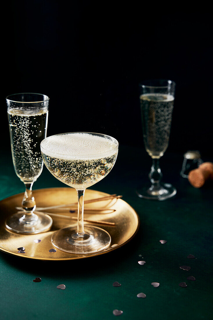 Prosecco glasses and golden plate on a green background
