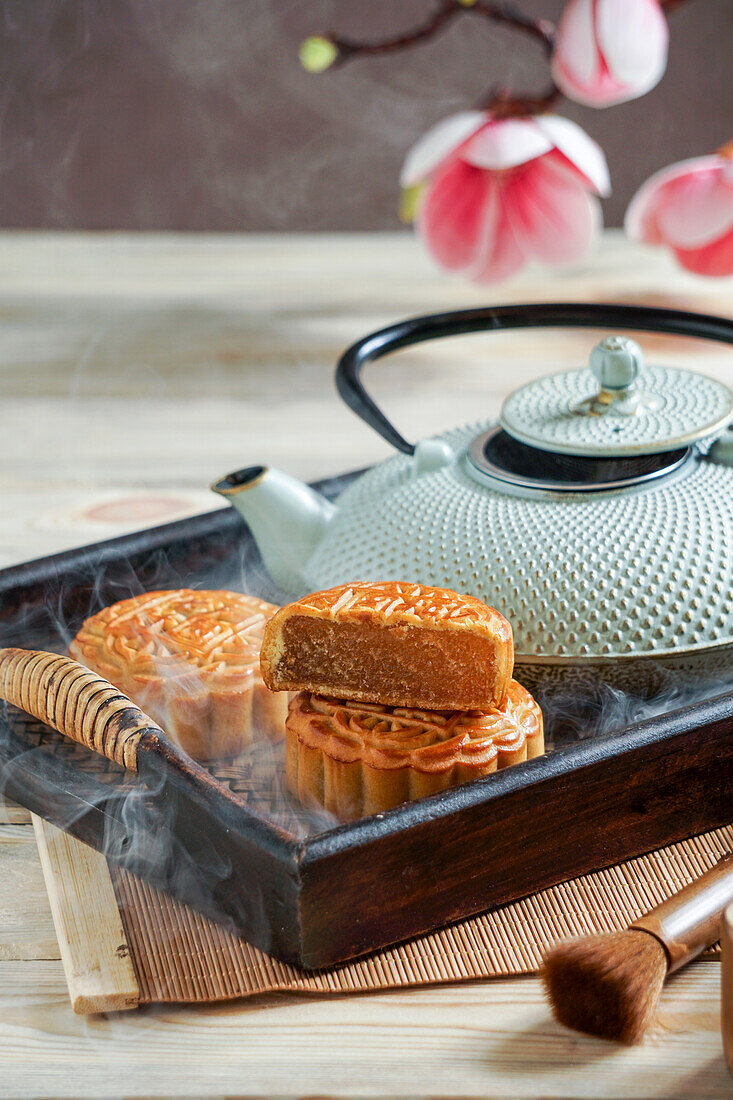 Moon cake for the Mid-Autumn Festival, concept for traditional Chinese feast on an Asian wooden tray with teapot