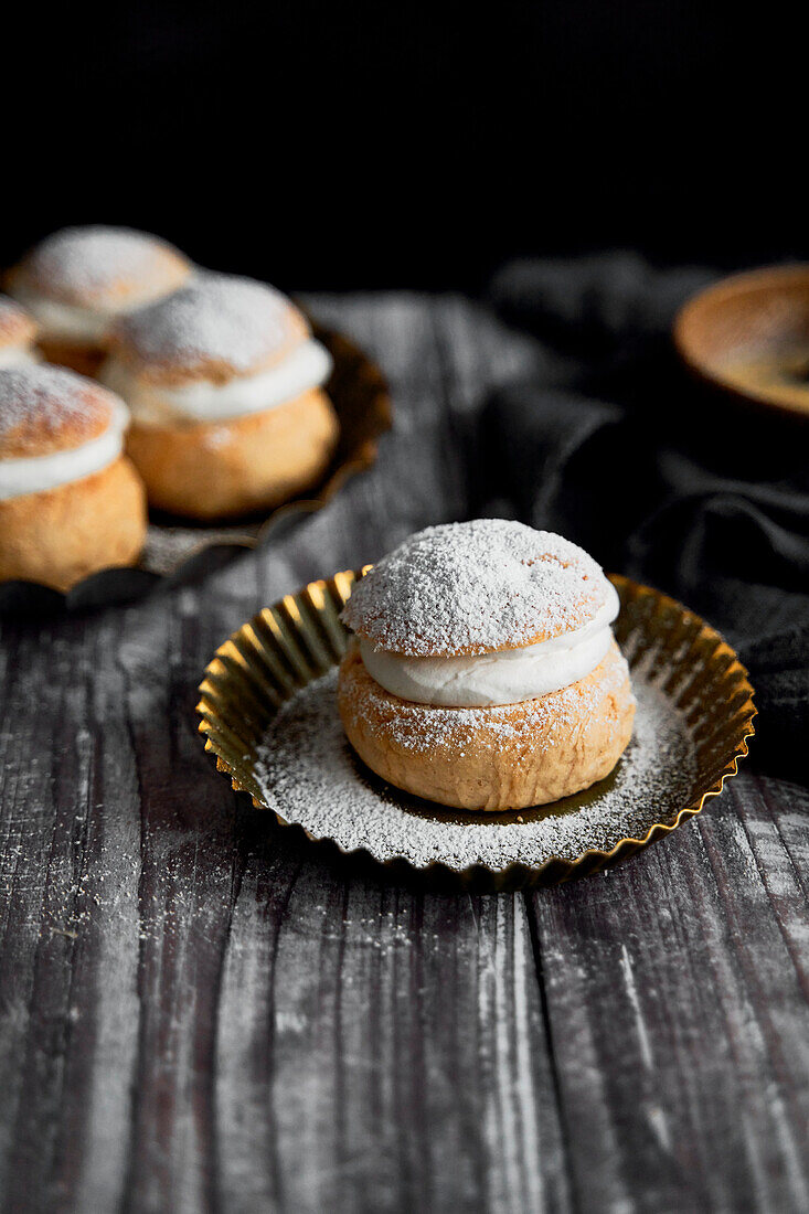 Semlor Buns on Wood Backdrop with icing sugar on tray