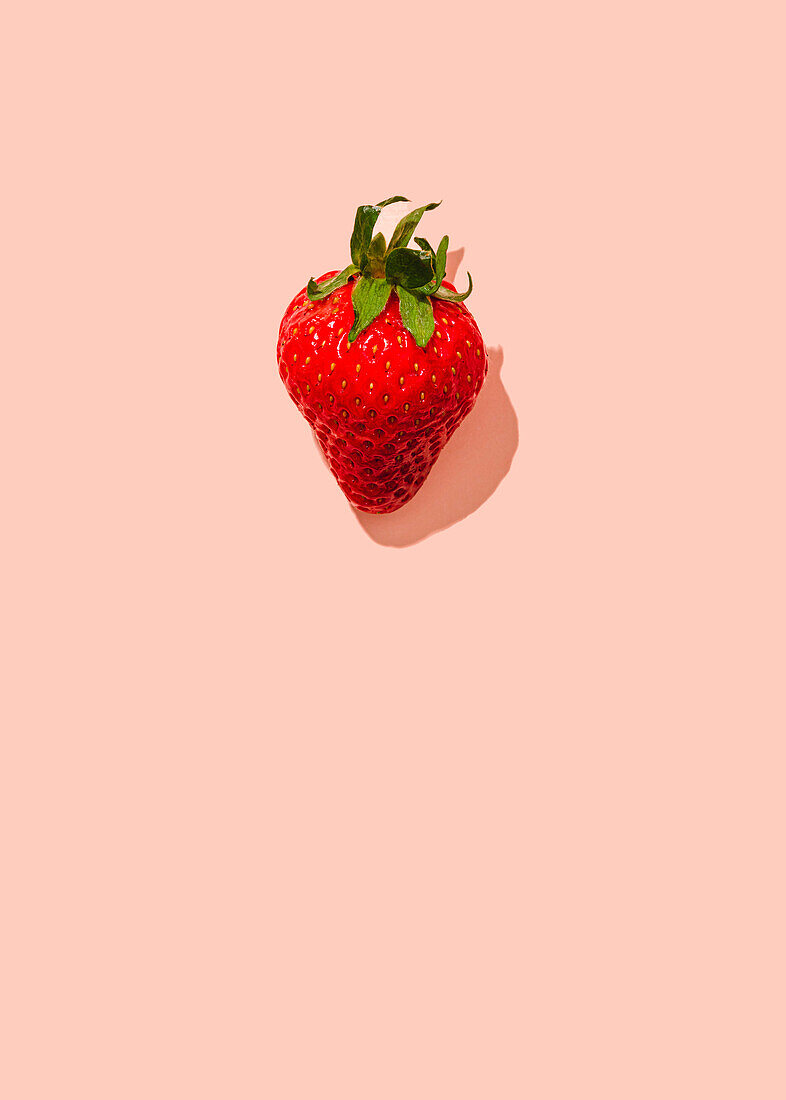 Single strawberry on pink background