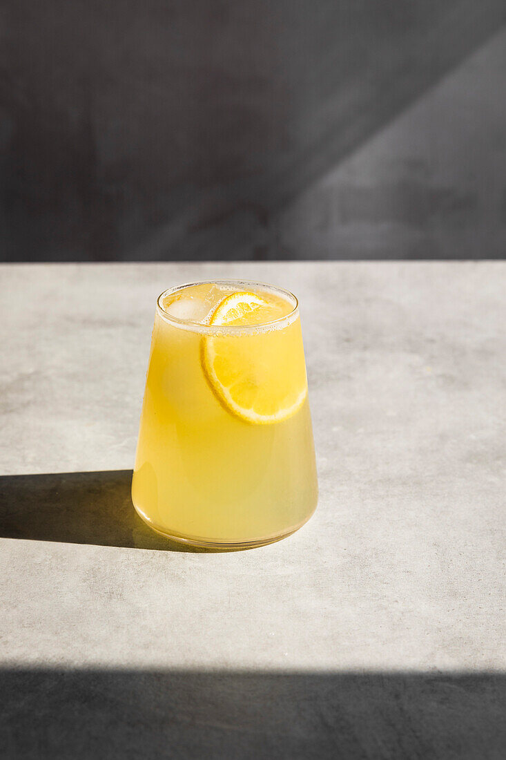 Homemade lemonade with ice and lemon slices in a glass.