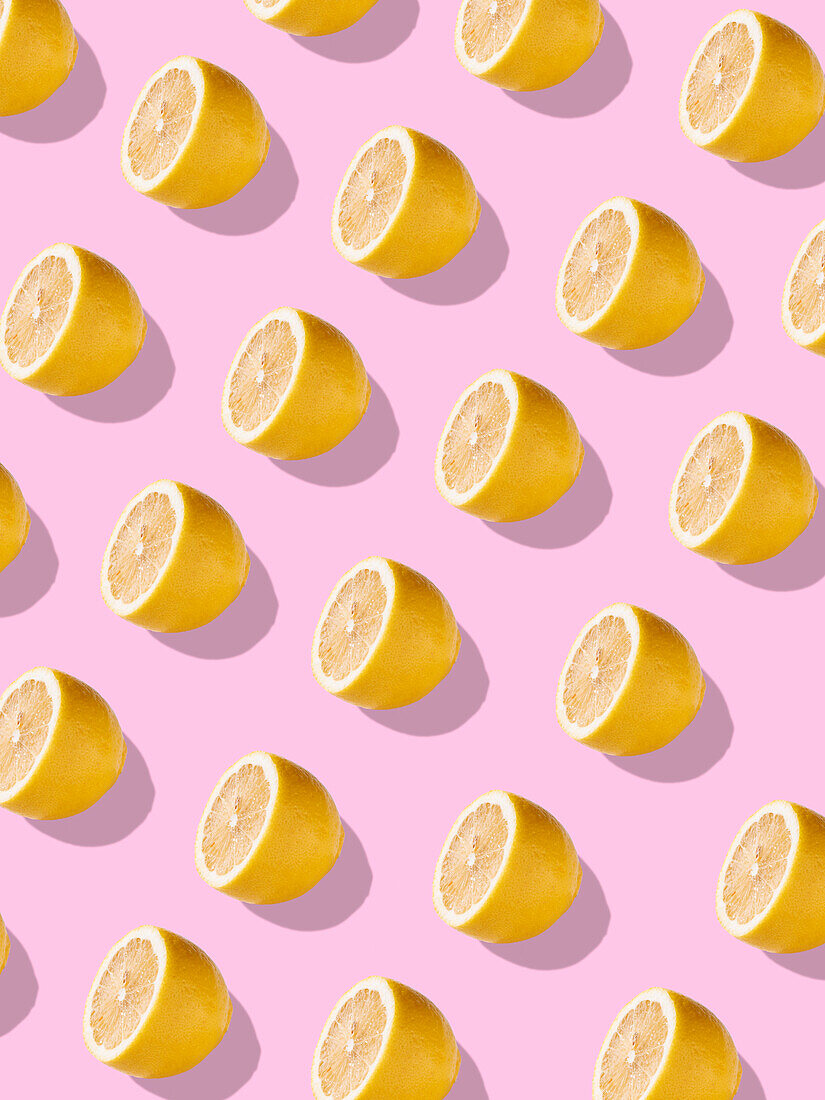 Full frame with juicy lemon halves against a light pink background