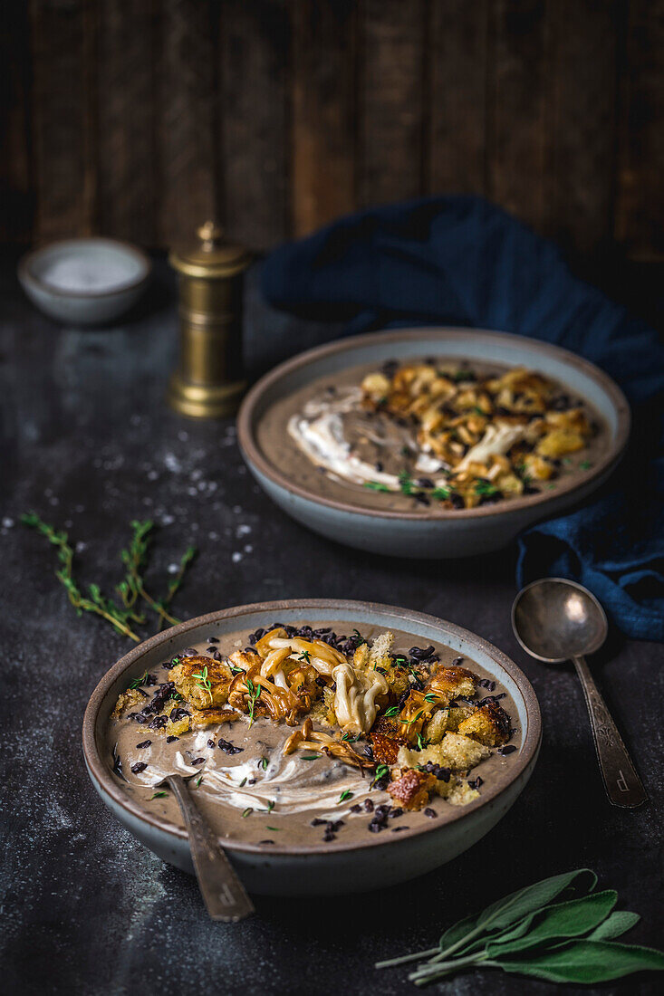 Zwei Schalen cremige Pilzsuppe mit gebratenen Muscheln und Crouton-Garnitur, Seitenwinkel