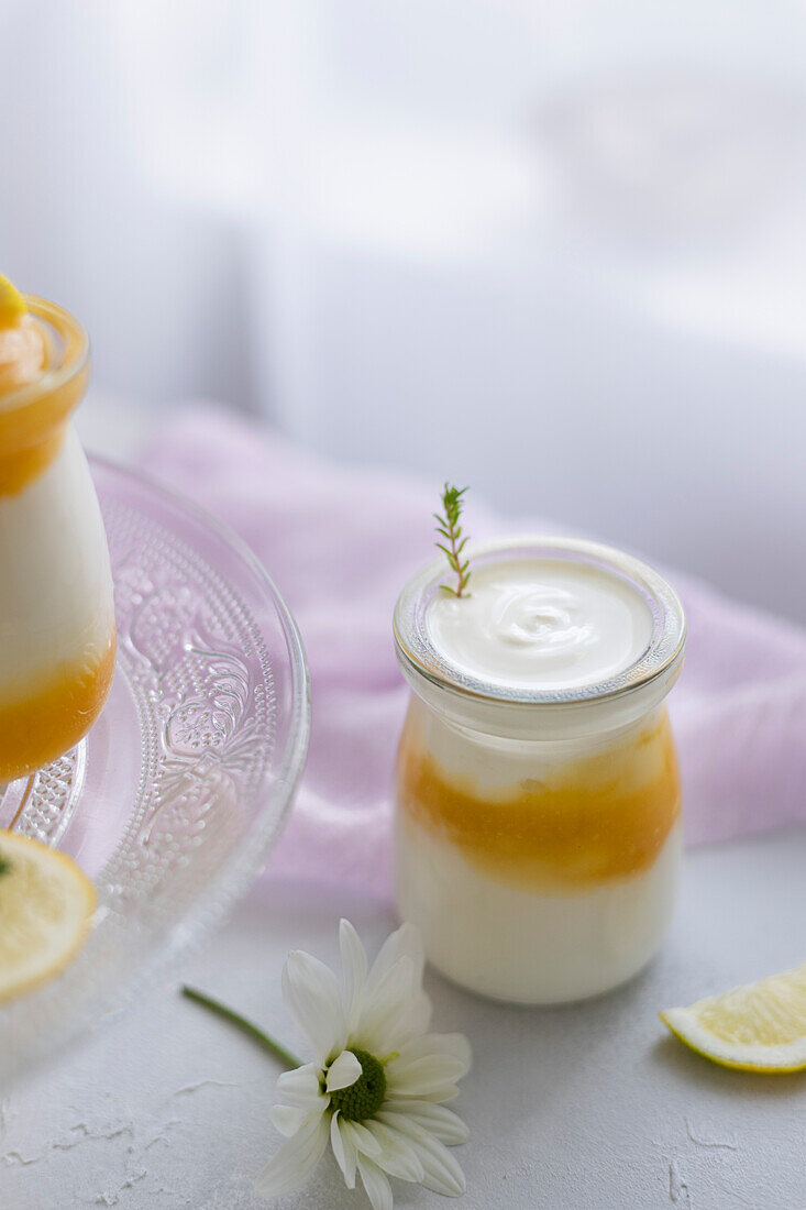 Lemon curd and greek yogurt with thyme in glass jars. Soft romantic scene.