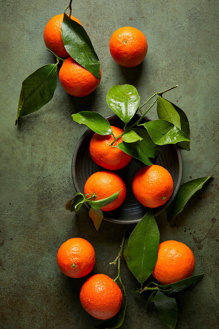 Mandarin oranges with stems and leaves on a green background