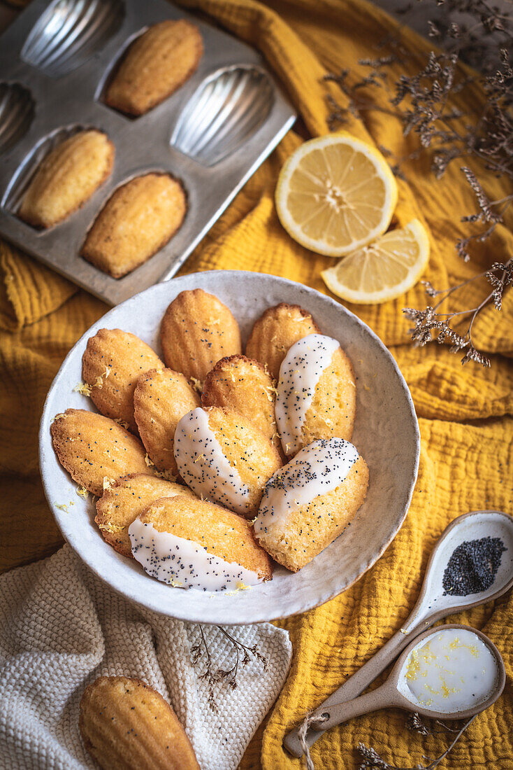 Zitronen-Madeleines mit Mohn vor gelbem Hintergrund