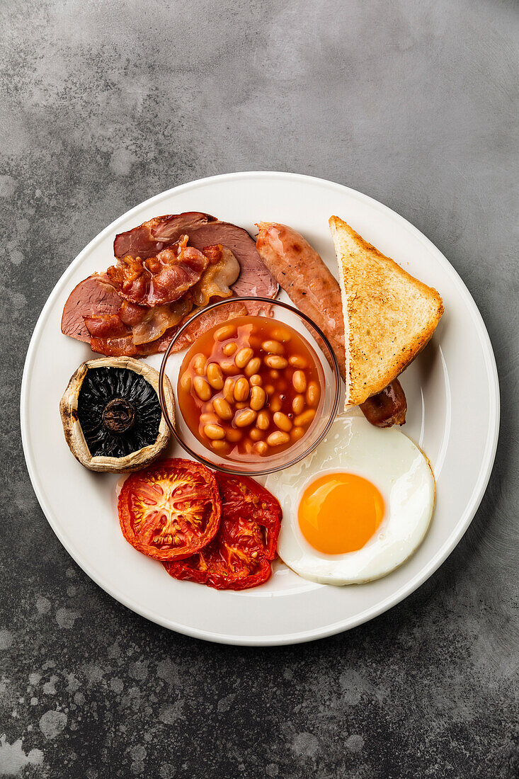 Komplettes englisches Frühstück mit Spiegeleiern, Würstchen, Speck, Bohnen und Toast