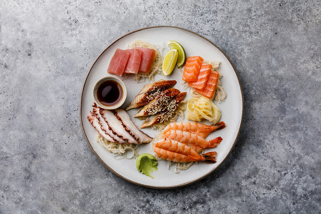 Sashimi-Sushi auf einem Teller vor grauem Hintergrund