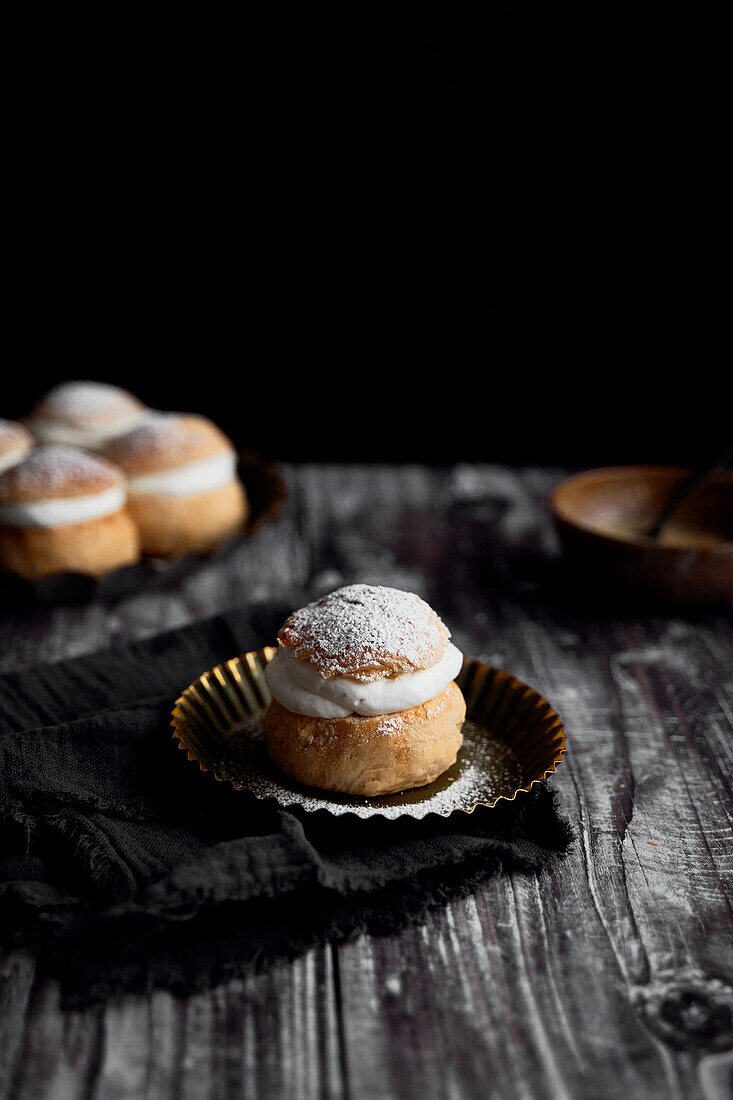 Semlor Buns on Wood Backdrop with icing sugar on tray