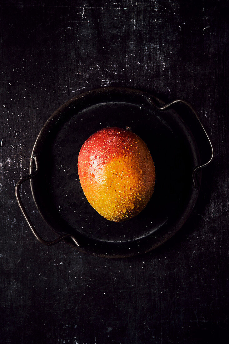 Fresh mango on a black tray and black background