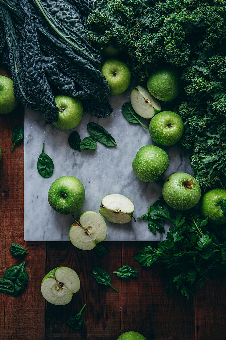 Eine Auswahl an gesunden grünen Lebensmitteln, darunter Äpfel und Grünkohl