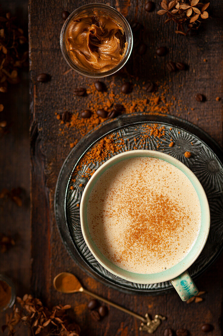 Ein süßes Milchkaffeegetränk mit Keksbutter und Kekskrümeln garniert. Präsentiert in einem Keramikbecher