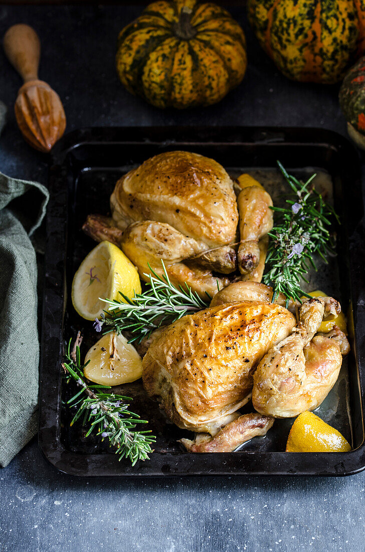 Roasted chicken on a baking tray with thyme and lemons