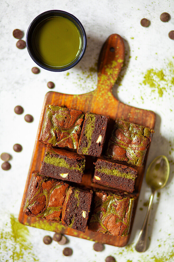 Chocolate brownies with matcha cheesecake, presented on a wooden paddle board