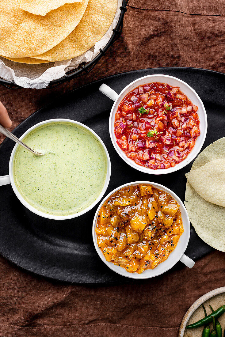 Drei Poppadom-Dips: Minz-Joghurt-Sauce, Chutney mit roten Zwiebeln, Mango-Chutney, serviert mit Poppadoms