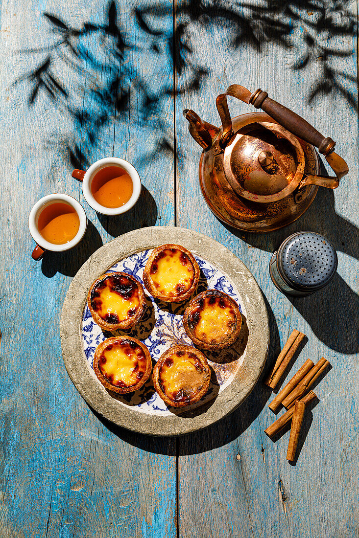 Pastel de Nata Frisch gebackene portugiesische Eierpuddingtorte und Tee auf blauem Holztisch