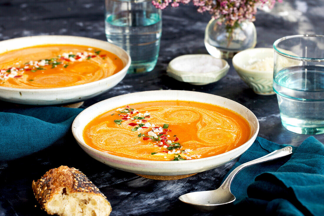 Red lentil piquillo pepper bisque in white bowls with blue napkins
