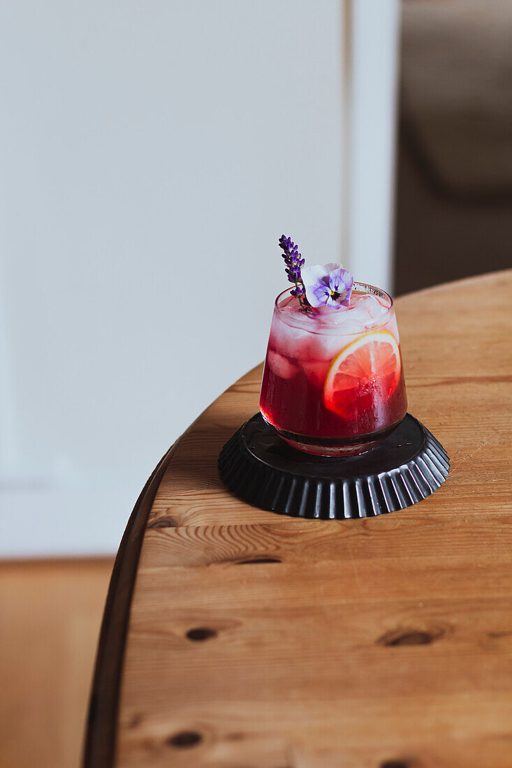 Summer cocktail with flowers on a wooden table