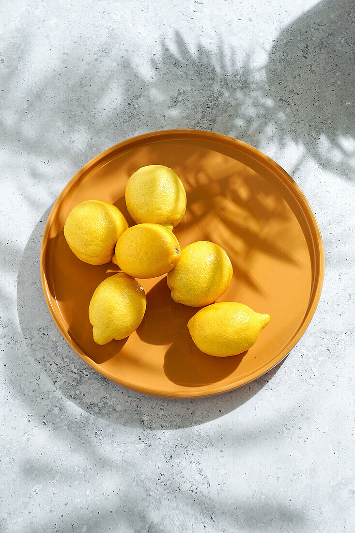 Fresh lemons on a yellow plate. hard sunlight and shadow