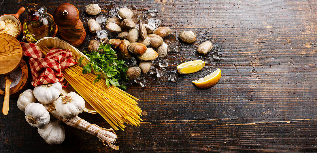 Dunkler Holzhintergrund mit Zutaten zum Kochen von Spaghetti vongole