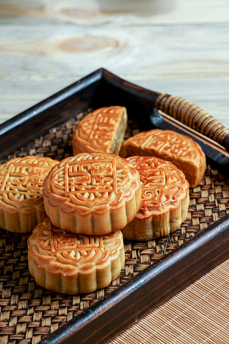 Mid-autumn festival moon cakes, concept for traditional Chinese holiday food on an Asian wooden tray