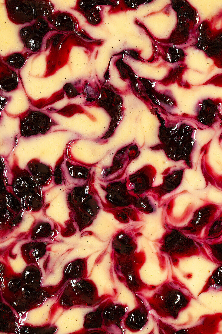 Close-up of the top of a baked cheesecake with blackcurrant ripples